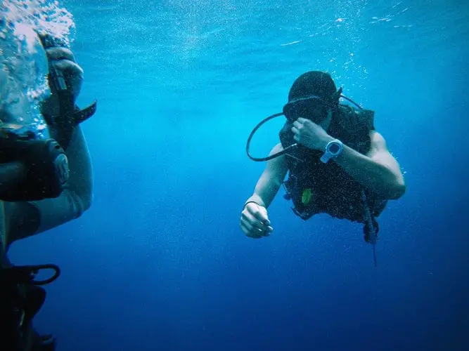 photo-1474203383385-8a34c1a55ebc diver holding nose underwater