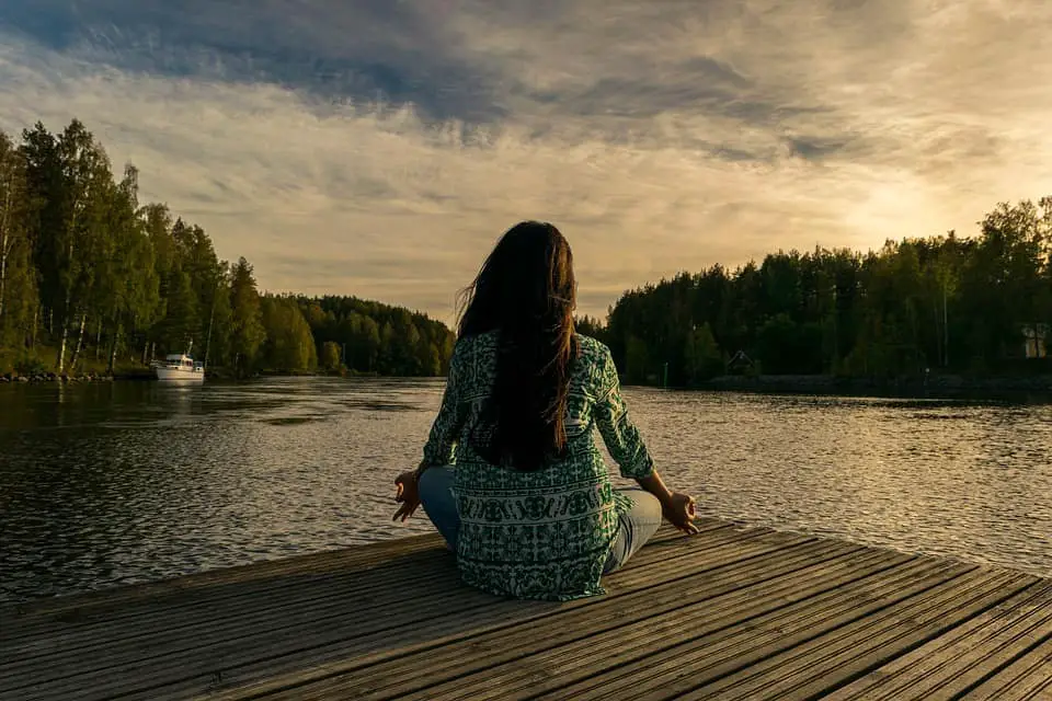 woman having yoga in nature lake