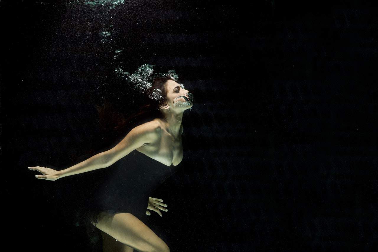 woman wearing black dress underwater