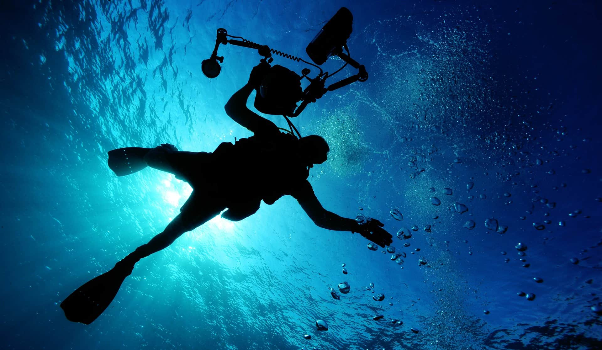 Diver holding a metal detector while swimming underwater