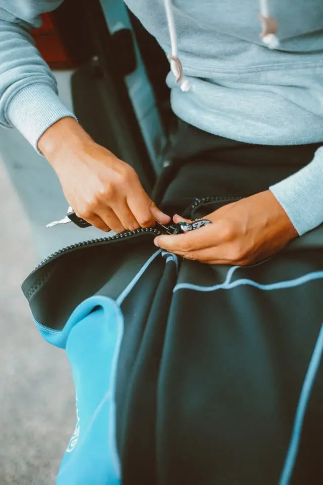 a man fixing the zipper of a wetsuit