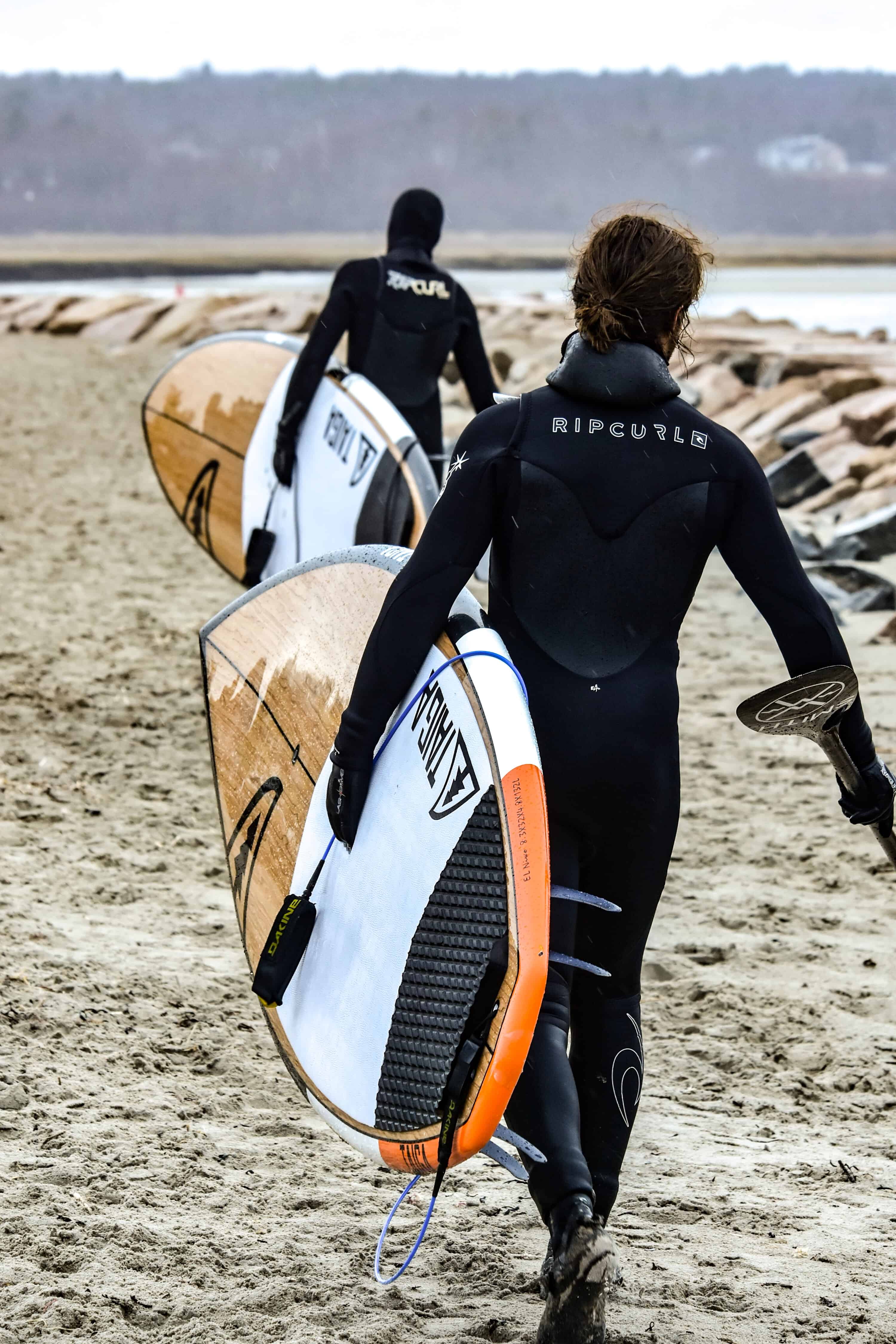 two people carrying their surf boards